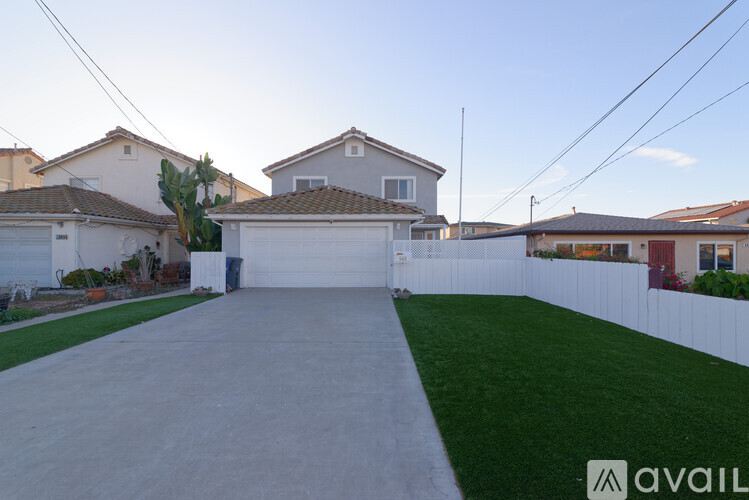 A house with a white fence and a driveway in front.