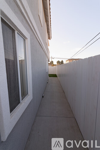 A narrow sidewalk runs between two white buildings.