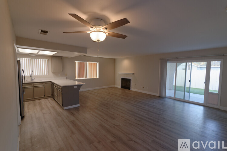 A spacious living room with a ceiling fan and sliding glass doors.