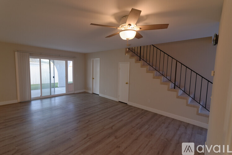 A spacious room with a ceiling fan and wooden flooring.