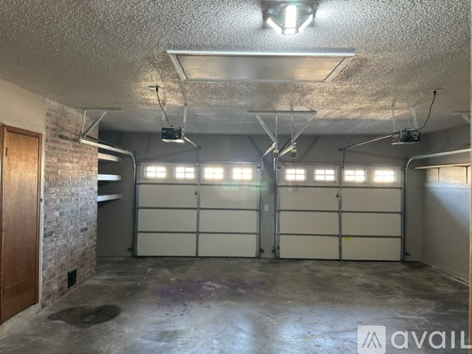 A spacious garage with two doors and a brick wall on the left side.