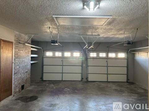 A spacious garage with two doors and a brick wall on the left side.