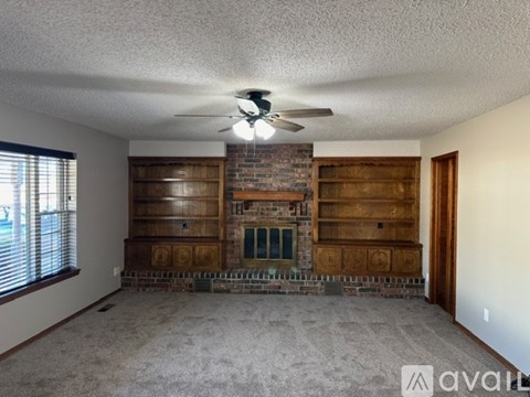 A living room with a fireplace and a ceiling fan.