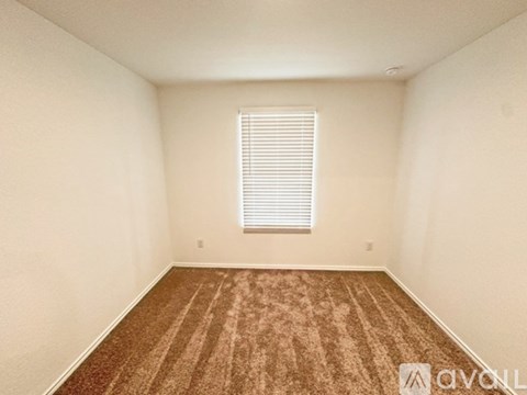 A room with a carpeted floor and a window with blinds.