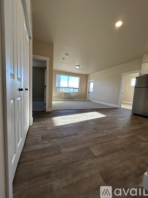 A spacious room with wooden flooring and white walls.