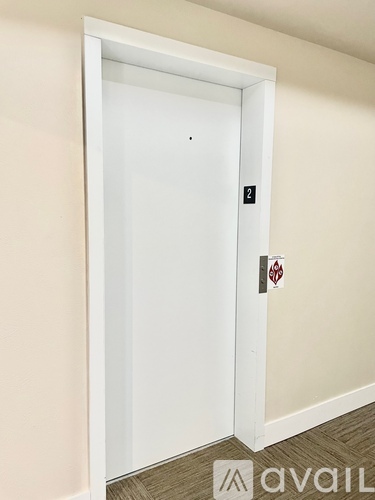 A white door with a black handle and a red sticker on it.