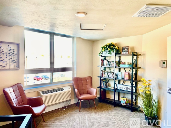 A room with a red chair, a brown chair, and a bookshelf.