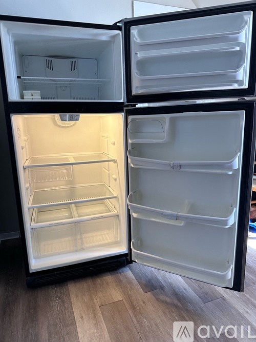 A black refrigerator with its door open showing the empty shelves.