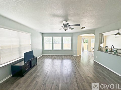 A spacious room with a ceiling fan and a flat screen TV.