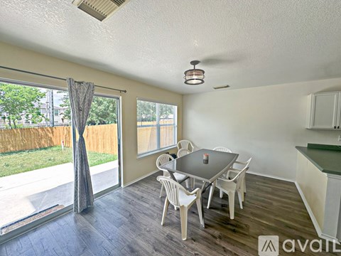 A dining room with a table and chairs and a sliding glass door.