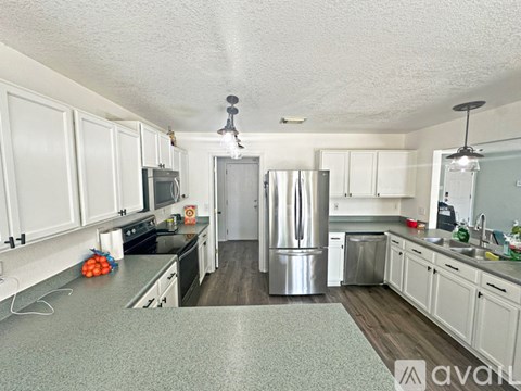 A kitchen with white cabinets and a stainless steel refrigerator.