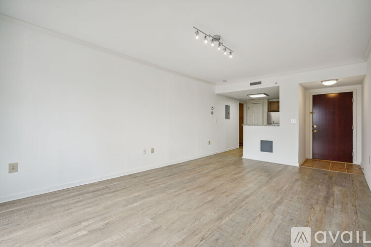 A spacious room with wooden flooring and a door on the right.