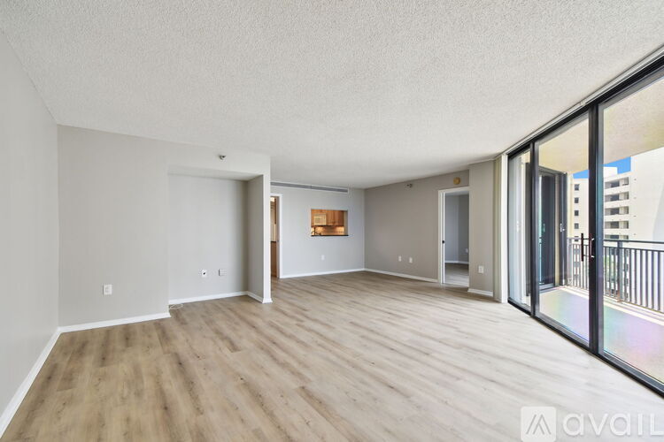 A spacious living room with wooden flooring and a balcony with a railing.