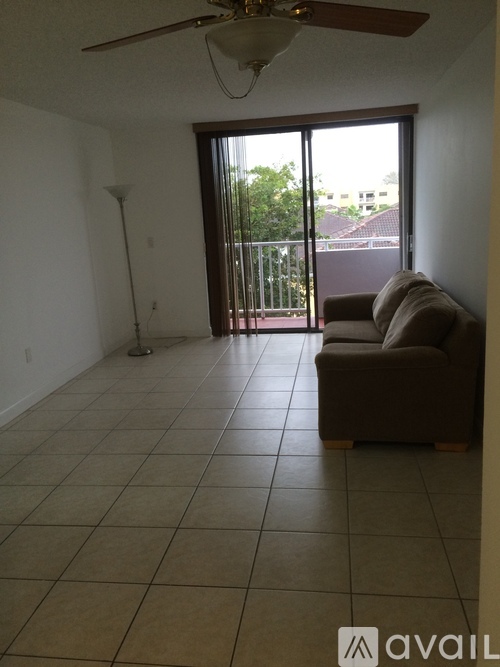 A living room with a couch, a fan, and a sliding glass door.