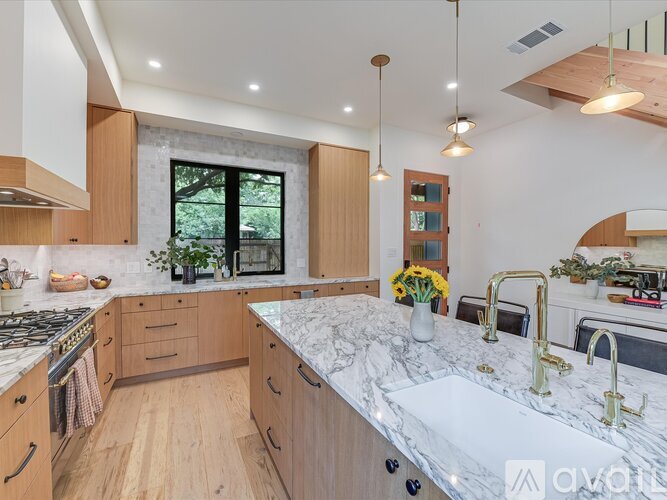 A modern kitchen with wooden cabinets and a marble countertop.