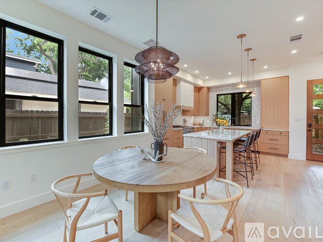 A modern dining room with a round wooden table and chairs.
