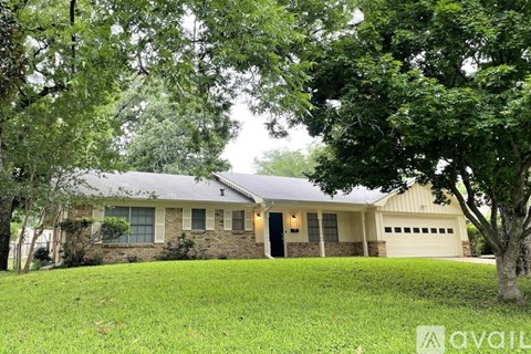 A house with a garage is surrounded by trees.
