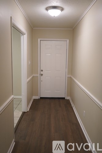 A hallway with a white door and wooden floor.