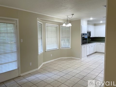 A kitchen with white cabinets and a tile floor.