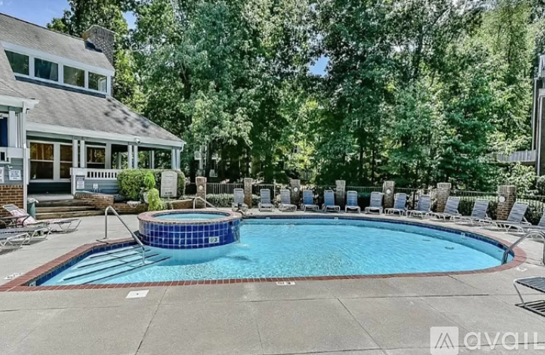A pool surrounded by trees and chairs.