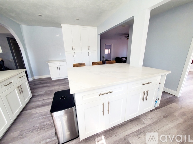 A kitchen with white cabinets and a stainless steel trash can.