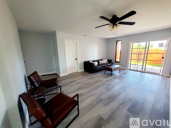A living room with a couch, chairs, and a ceiling fan.