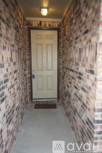 A hallway with a white door and brick walls.
