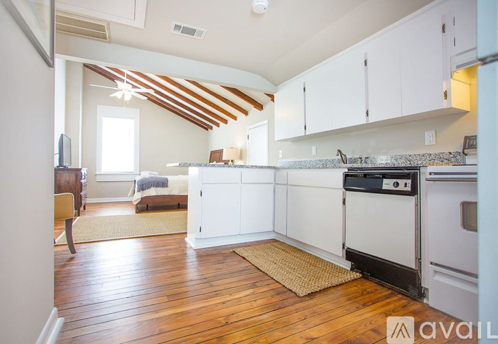 A kitchen with white cabinets and a wooden floor.