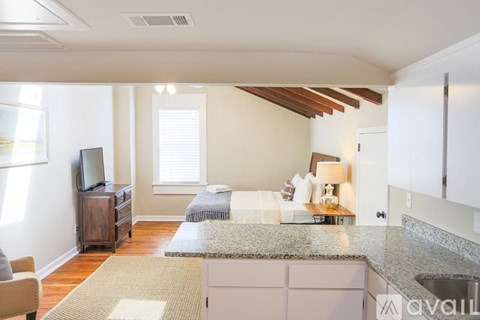 A kitchen with granite countertops and a bedroom with a bed and a window.