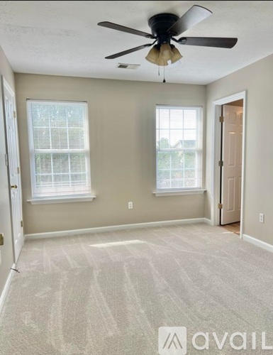 A room with a fan and two windows.