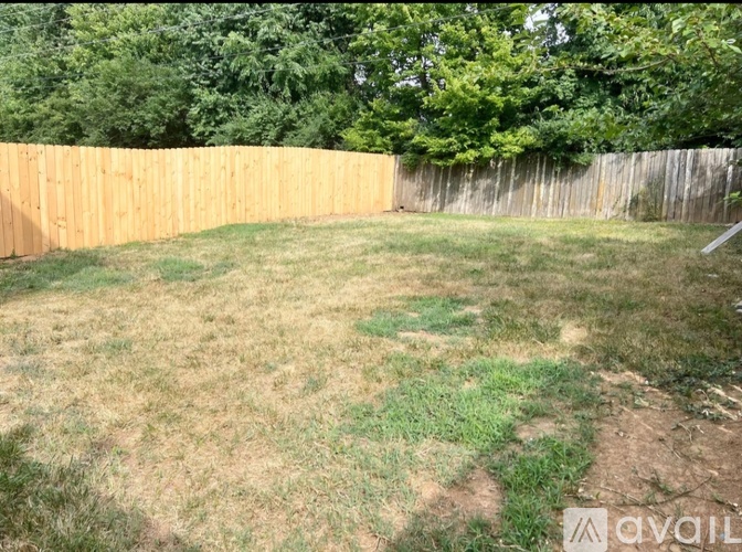 A backyard with a wooden fence and a grassy area.