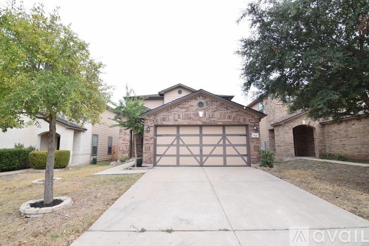 A house with a garage and a tree in front.