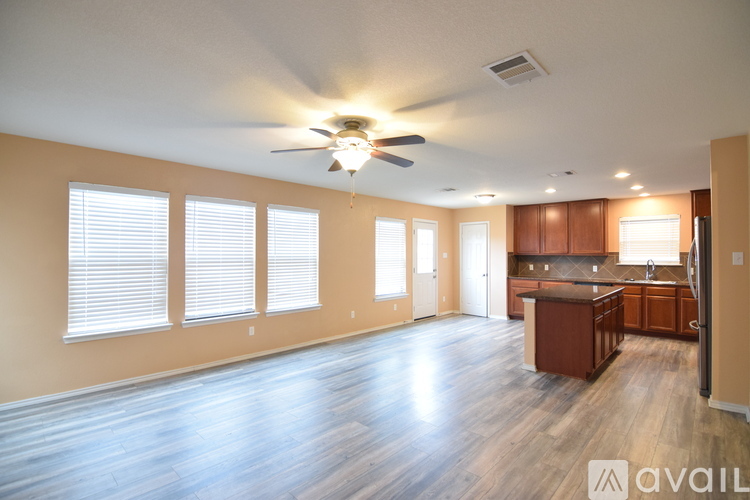 A spacious living room with a ceiling fan and hardwood floors.