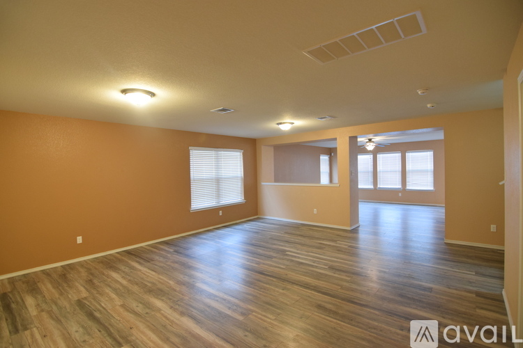 A spacious room with wooden flooring and a large window.