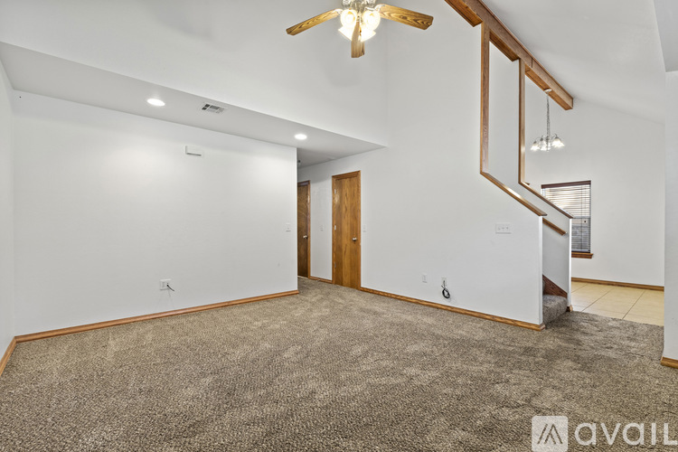 A spacious room with a carpeted floor and a wooden staircase.