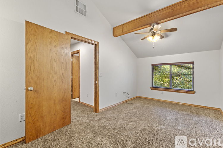 A room with a ceiling fan and a window with a view of trees.