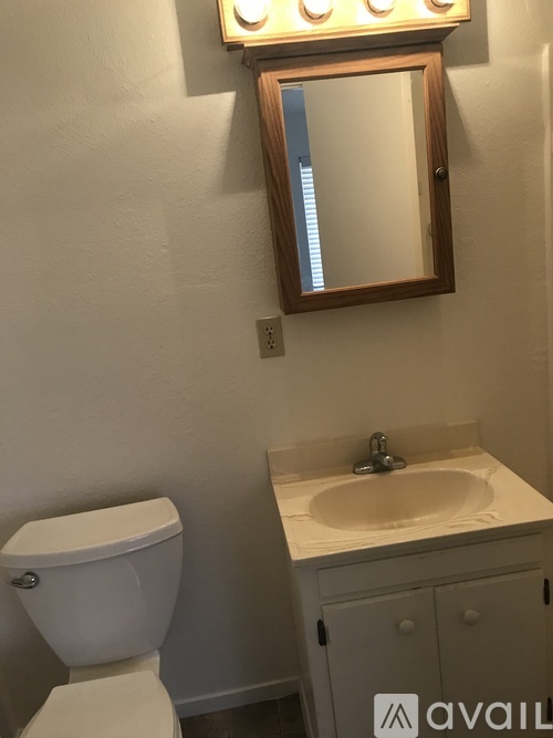 A bathroom with a toilet, sink and mirror.