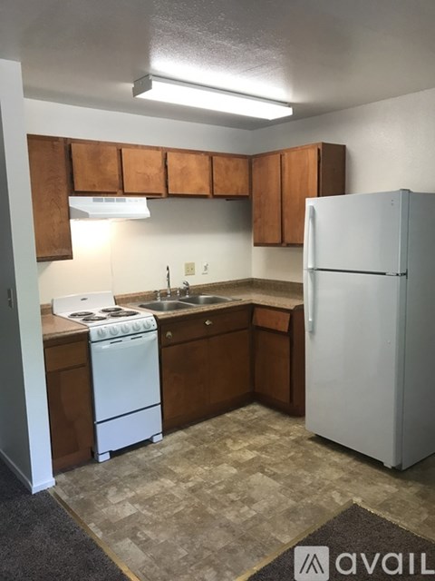 A kitchen with a white refrigerator, white stove, and brown cabinets.