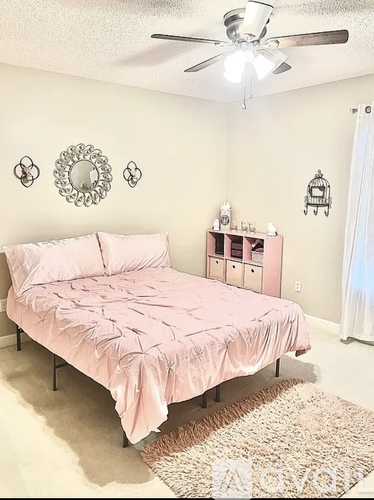 A bedroom with a pink bed and a ceiling fan.