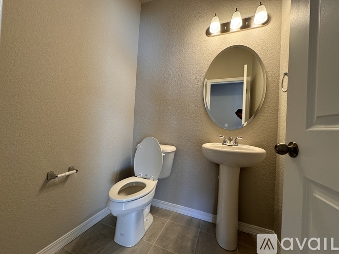 A bathroom with a toilet, sink, and mirror.