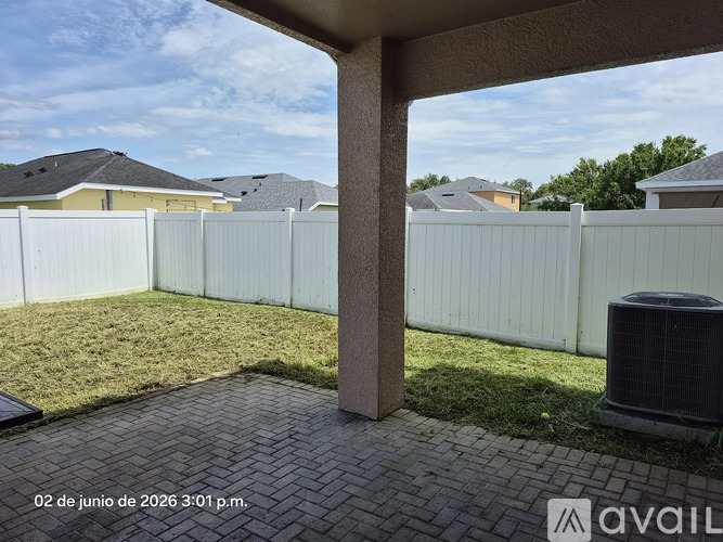 A patio area with a white fence and a brick walkway.