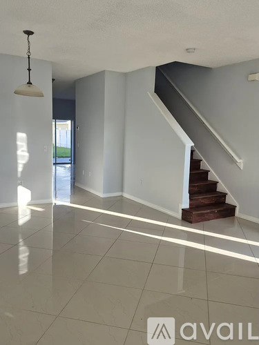 A spacious room with a staircase and a hanging light fixture.