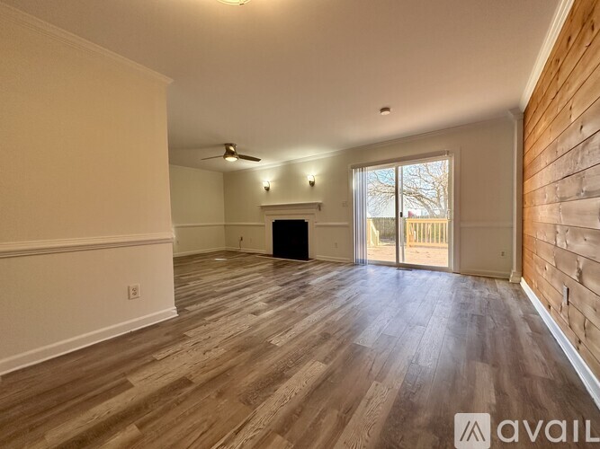 A spacious living room with wood flooring and a fireplace.