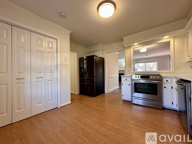 A kitchen with white cabinets and a black fridge.