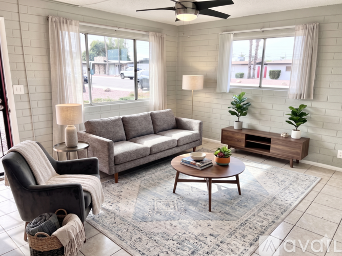 A living room with a grey sofa, a black chair, a wooden coffee table, and a rug.