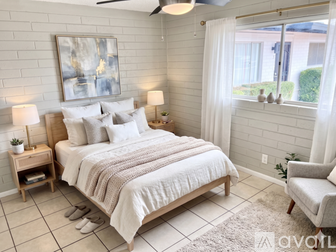 A bedroom with a large bed, a ceiling fan, and a painting on the wall.