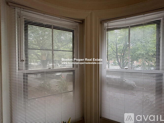 A room with two windows covered in white blinds.