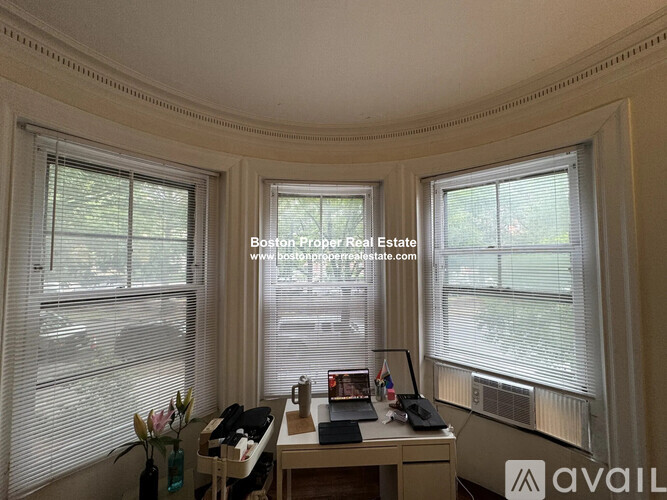 A room with a desk and a window with blinds.