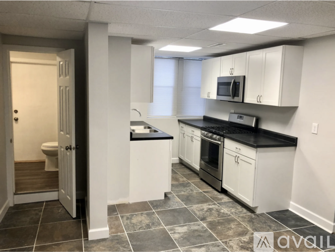 A kitchen with white cabinets and black countertops.