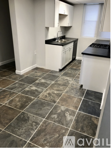 A kitchen with a tiled floor and white cabinets.